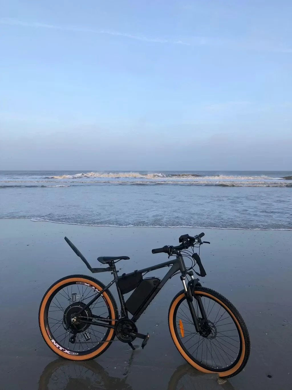Customer bike converted with a KirbEbike rear hub motor kit and frame battery, parked on a beach